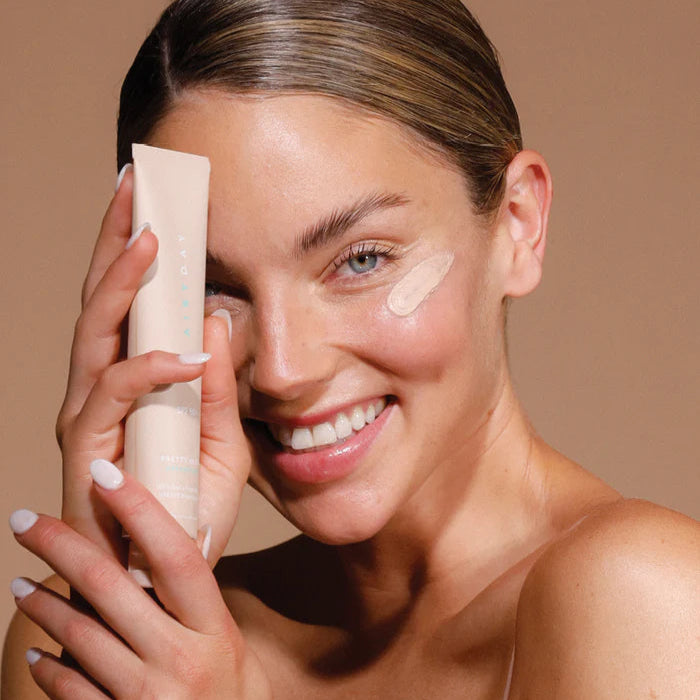 Woman applying spf50+ to her face with a beige background